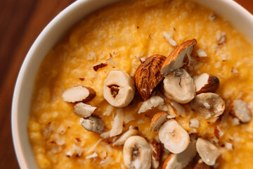 corn porridge with nuts in a white bowl, vertical photo