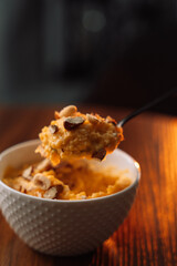corn porridge with nuts in a white bowl, vertical photo