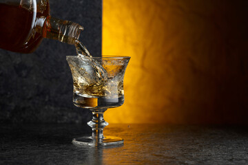 Pouring strong alcoholic drink from a bottle into a glass.