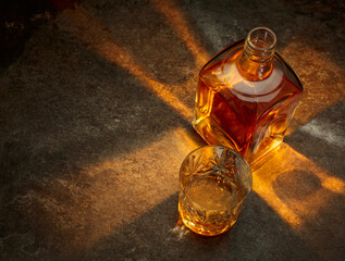 Bottle and crystal glass of whiskey on a stone table.