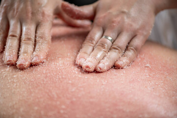 Scrubbing back massage with salts exfoliates the skin, removes dead skin cells, unclogs pores, and promotes smoother, healthier skin, offering relaxation and revitalization in a spa setting