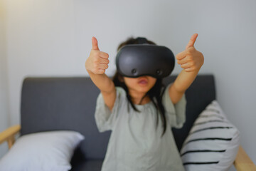 Girls in VR goggles on grey couch studio shot. 
