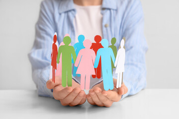 Woman holding paper human figures at light table. Diversity and inclusion concept