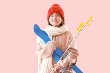 Little Asian girl with skis on pink background