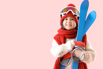 Little Asian girl with skis on pink background