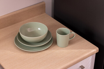 Holder with clean dishes near sink on counter in kitchen