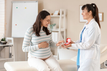 Obraz premium Young pregnant woman receiving pills from doctor in clinic