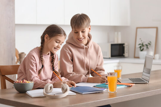Teenage boy with his sister doing homework in kitchen