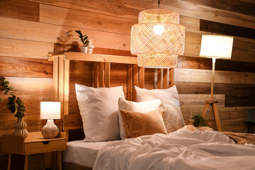 Cozy bed and glowing lamps in stylish bedroom at night