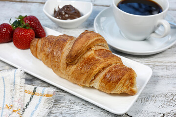 kruvasan cup of coffee and croissant on a rustic white wooden	

