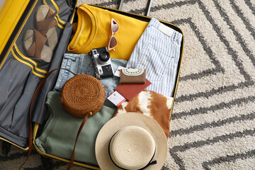 Unpacked suitcase with clothes and travelling accessories in hotel room