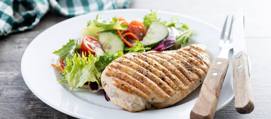 Healthy grilled chicken with salad on wooden table