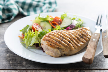 Healthy grilled chicken with salad on wooden table