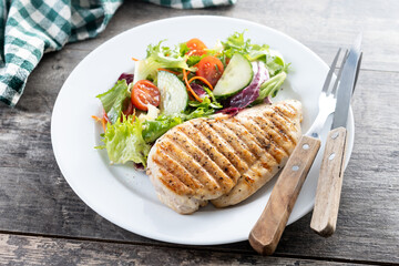 Healthy grilled chicken with salad on wooden table