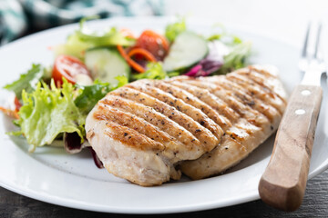 Healthy grilled chicken with salad on wooden table. Close up