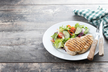 Healthy grilled chicken with salad on wooden table. Copy space
