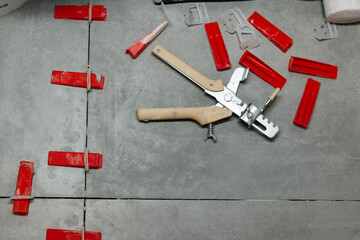 Tool and tile positioning setup for floor installation work on grey concrete tiles in a home renovation project