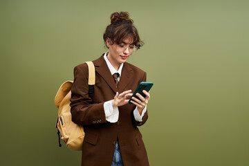 Young womans stylish outfit shines while she checks her phone in a vibrant green setting