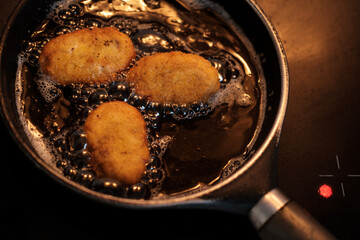Frying delicious chicken croquettes in a pan with hot oil on a modern stove