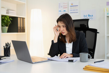 A young businesswoman is sitting doing paperwork,She has a worried look on her face.