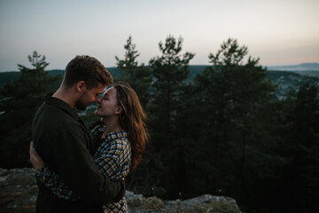 Fototapeta premium Beautiful young woman in the arms of her boyfriend at sunset in the mountains.