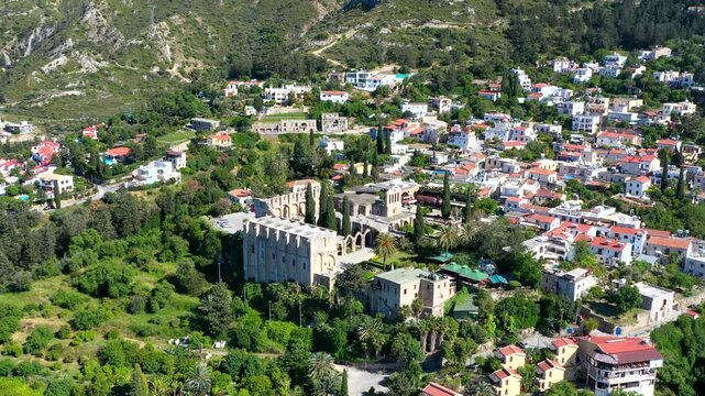 Camera pans over the Bellapais Abbey and the surrounding village, showcasing the beautiful architecture and lush greenery. Kyrenia District, Cyprus
