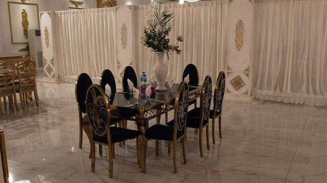 Elegant Banquet Hall with Luxurious Round Table Setup : A grand banquet hall featuring a lavish round table with black velvet chairs, floral centerpiece, and golden decor. Perfect for weddings, recept