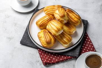 French eclair with custard. Profiteroles with cream on a white plate. Side view. Homemade pastries...