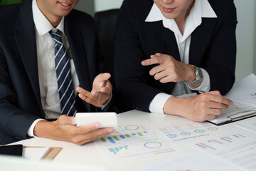 Strategic Planning and Data Review. Business partners discussing analytics on a mobile device, focusing on key performance indicators.