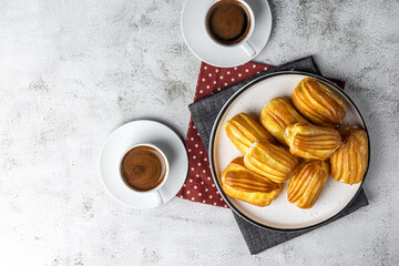 French eclair with custard. Profiteroles with cream on a white plate. Top view. Homemade pastries with cream. Grey background. Profiteroles with coffee. Copy space