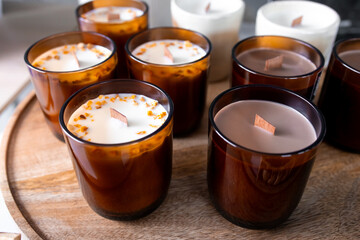 Scented brown and white candles with wooden wicks on a wooden tray