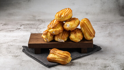 French eclair with custard. Profiteroles with cream on a white plate. Side view. Homemade pastries...