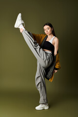 Young woman showcases stylish streetwear in dynamic pose against green backdrop