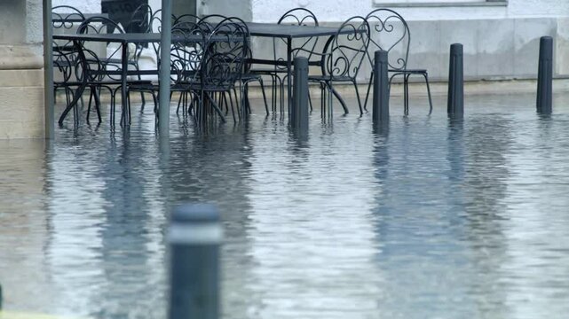 LD Tables and chairs in front of a bar as the sea level rises and is flooding the coastal town
