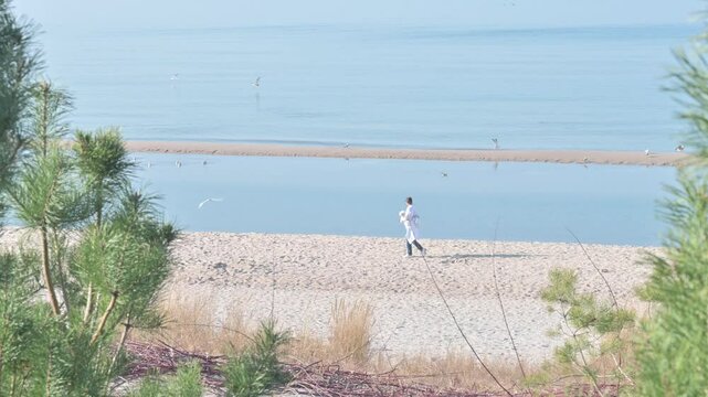 Woman with dog and joggin men on Sunny Beach, Miedzyzdroje Poland.