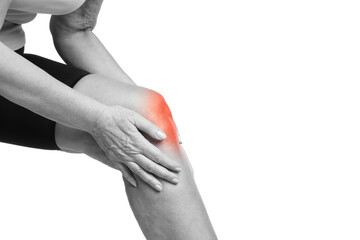 Senior woman suffering from pain in knee, closeup. Black-and-white effect with red color accent