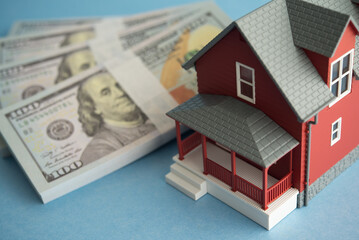 House and US dollar banknotes on blue background. Financial planning for home buying, mortgage...