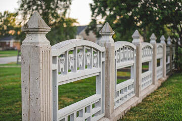 Decorative white wooden fence near a residential area during sunset, emphasizing craftsmanship and design details