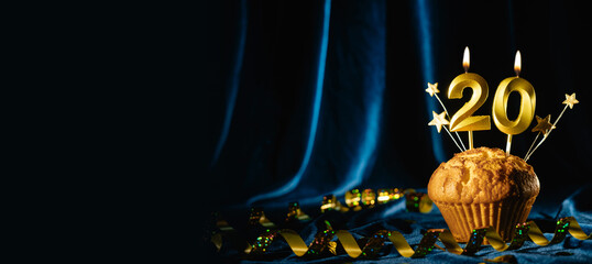 Coming age party 20th birthday. chocolate cupcake with number twenty candle on velvet blue background. Banner
