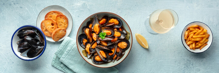 Mussels with French fries panorama, with toasted bread, lemon, and white wine, overhead flat lay shot of moules frites, panoramic banner