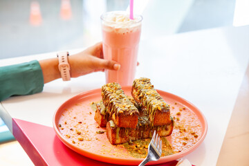 Female enjoying french toast kunafa style served with milk shakes at a fancy cafe restaurant.  