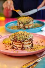 Girl friends eating dubai chocolate kunafa pancakes served at a fancy restaurant cafe.