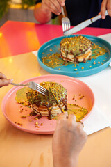 Girl friends eating dubai chocolate kunafa pancakes served at a fancy restaurant cafe.