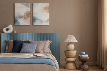 Cozy bedroom setting with a blue paneled headboard, neutral bedding, and abstract wall art in warm...