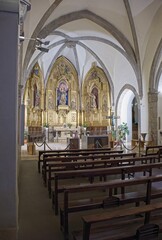 Fototapeta premium Santa Pau, Spain - Feb 24, 2025: Church Santa Maria. Walking in Santa Pau suburb. Streets, buildings. Lifestyle in the urban area. Cloudy winter day. Selective focus