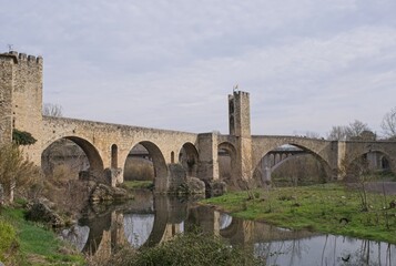 Besalu, Spain - Feb 24, 2025: People walking on Besalu bridge. Streets, buildings. Lifestyle in the urban area. Sunny winter day. Selective focus