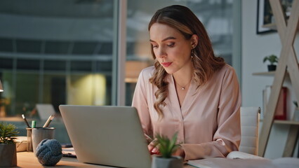 Obraz premium Late businesswoman using laptop in cozy office closeup. IT employee taking notes