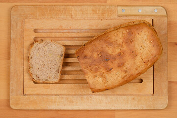 A top-down shot shows a loaf of homemade walnut bread, with one slice cut, on a wooden cutting board
