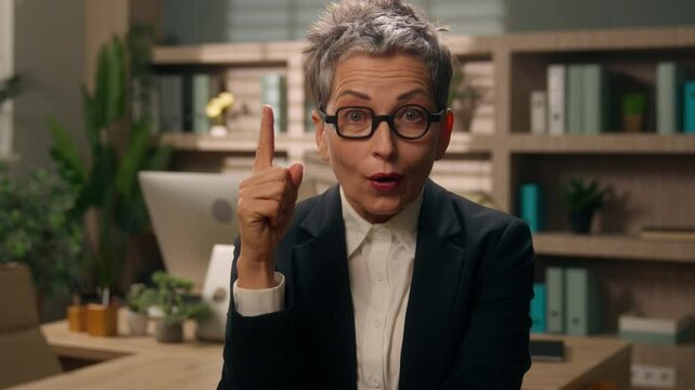 Portrait in office pensive thinking solution thoughtful unsure serious gray haired elderly mature senior old businesswoman business woman female come up with idea insight find answer looking at camera