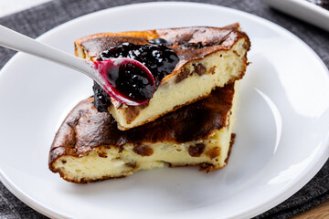 Cottage cheese casserole with berry jam on a white plate. Homemade casserole with cottage cheese and raisins.